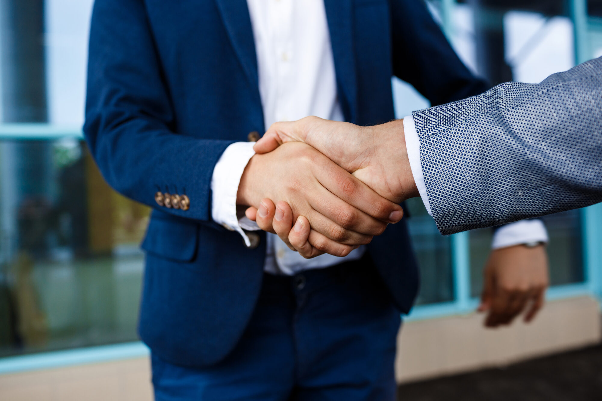 Uścisk dłoni dwóch osób w garniturach, partnerstwo w biznesie